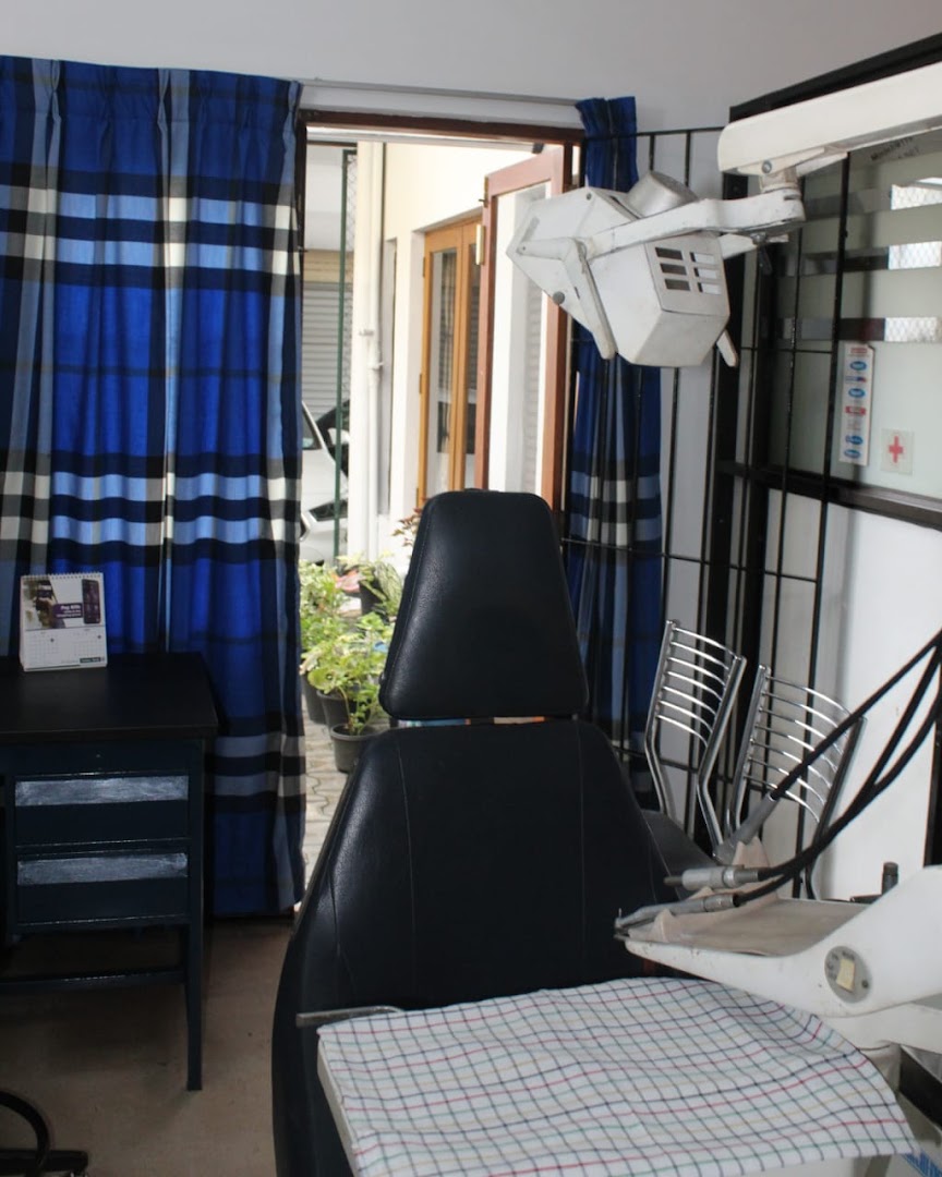 Black dental chair beside blue curtains and examination equipment