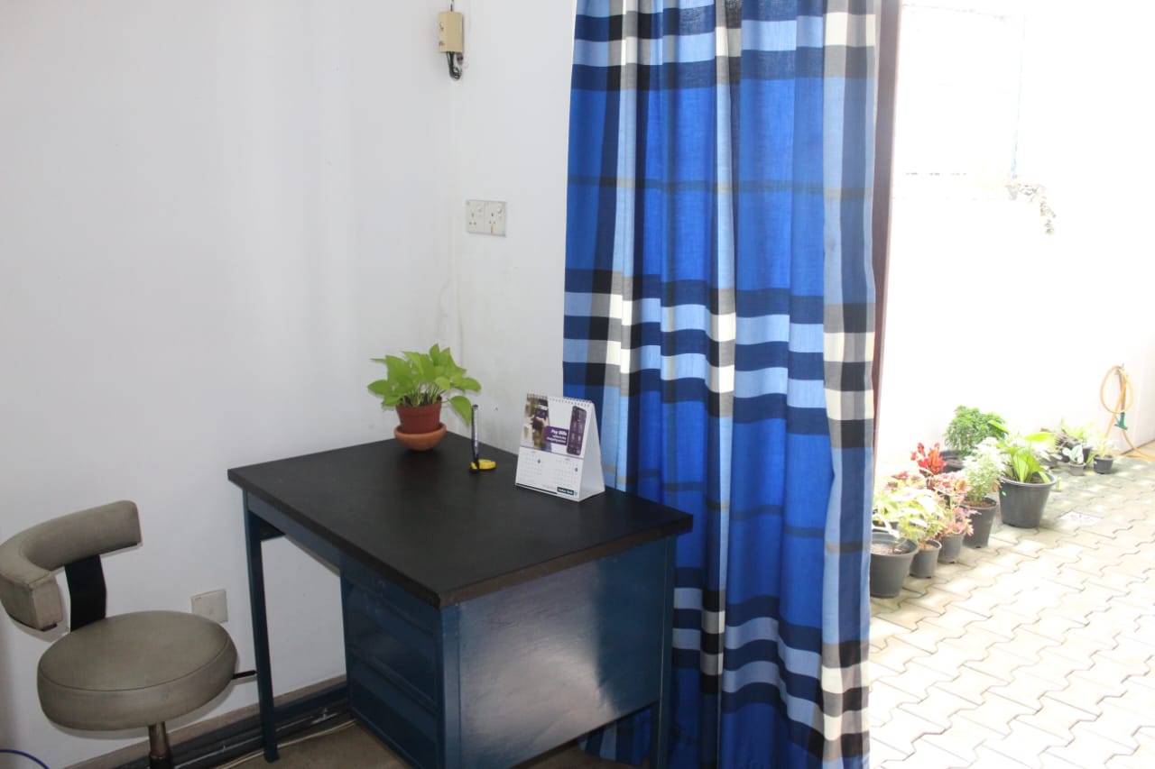 Desk and potted plant beside blue curtains